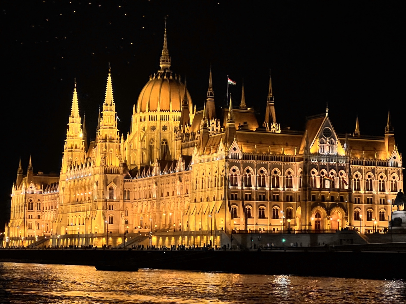 Gold beleuchtetes Parlament in Budapest bei Nacht am Donauufer